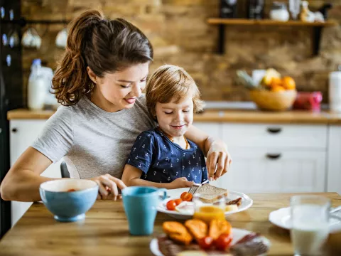 A Mother Feeds a Picky Eater Child at The Kitchen Table.