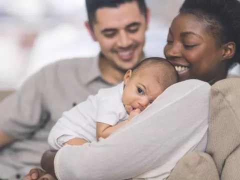 A New Mom Holds Her Baby While While Her Husband Smiles