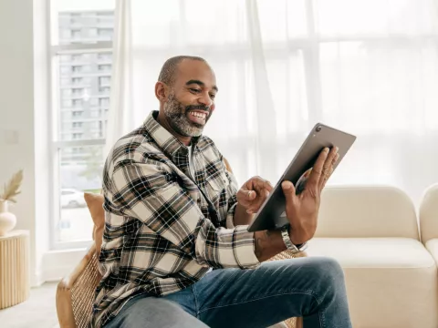 A Man Smiles During a Video Call on His Tablet in His Home.