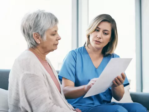 A Health Care Provider Goes Over Paperwork with a Patient at the Hospital.