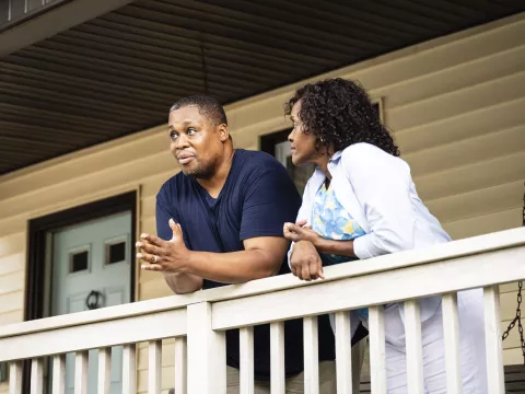 A middle-aged couple standing on the porch together