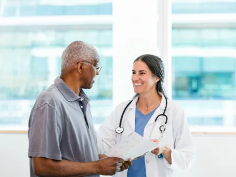 A Physician Smiles While She Goes Over a Patient's Chart With Him