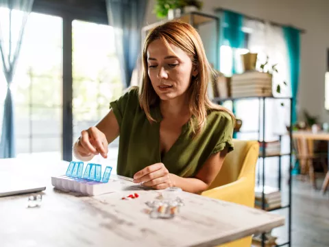 A Woman Fills Her Pill Box at Home.