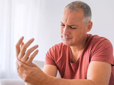 A Man Looks at the Palm of His Hand in Pain