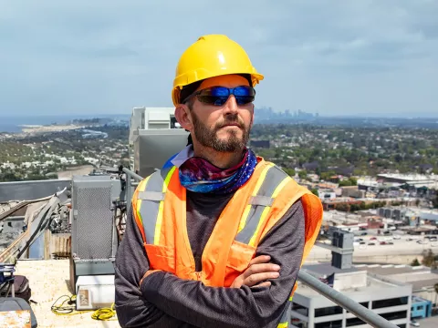 A Construction Worker Looks Off in the Distance While on a Roof