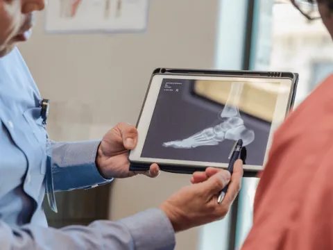 A doctor shows a patient an x-ray of a foot.