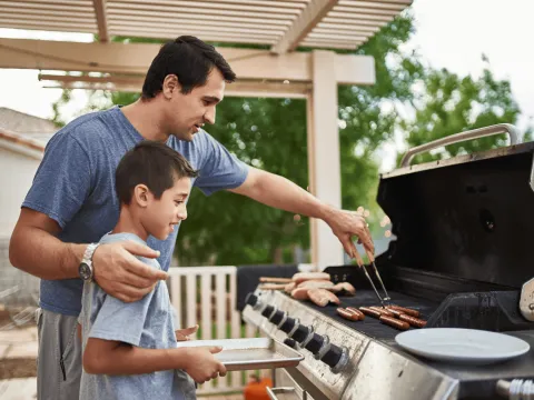 A Father Teaches His Son How to Use a Barbecue Grill