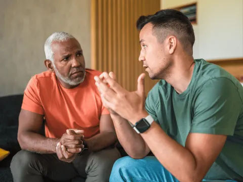 Two Men Sit and Talk in a Home