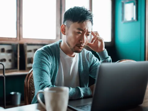 A Man Reads His Laptop at the Table