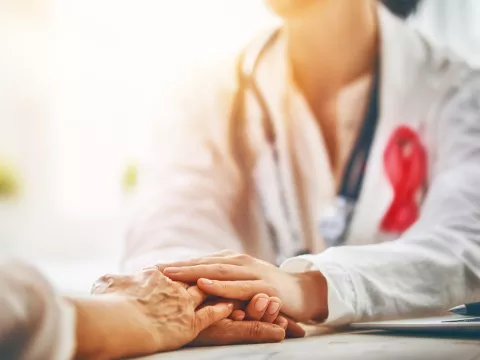 Female doctor placing hand on patient's hand.