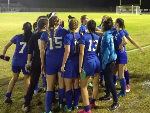 Girls soccer team in a huddle.