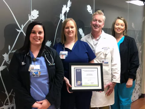 A group of co-workers standing next to each other while holding an award.