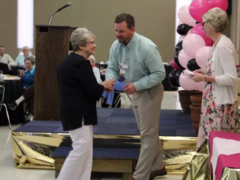 A group of two women and a man receiving an award at a ceremony.