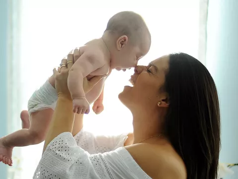 A mother holds her baby up.