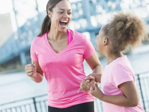 A mother and daughter are jogging together outside.