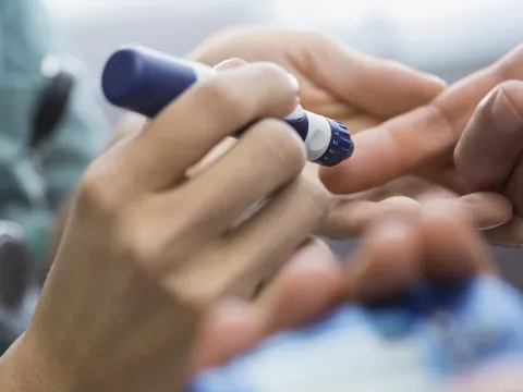 A diabetic patient takes a finger prick reading from an insulin pen.