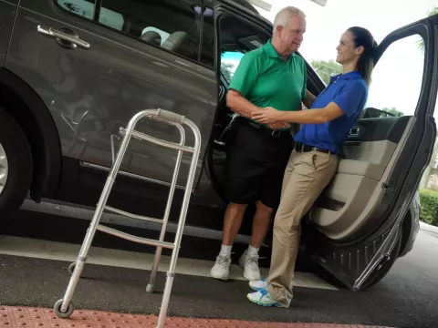 Senior receiving help out of a car