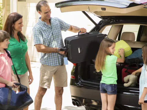 A family packs their car full of luggage.