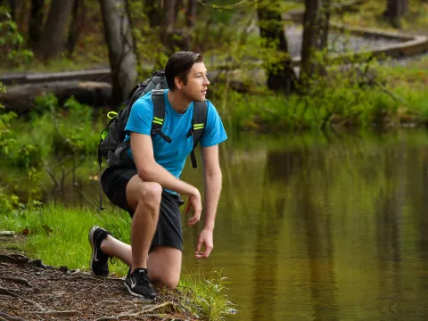 Taking a rest near a lake while hiking through the woods.