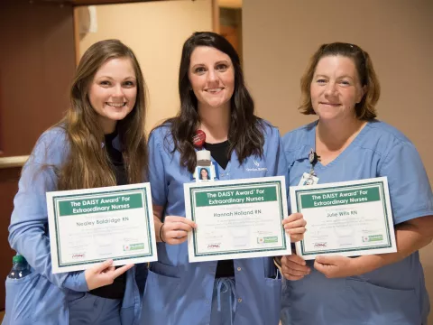 Three women holding an award.