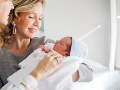 A new grandma visits a newborn in the hospital.