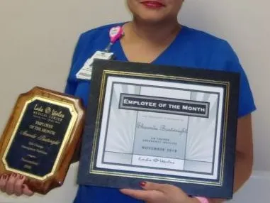 A female nurse holding two awards.
