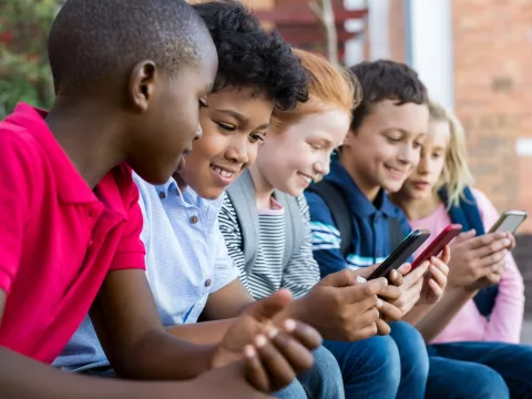 A group of kids use cell phones after school.