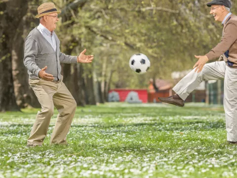 Seniors playing soccer in a park