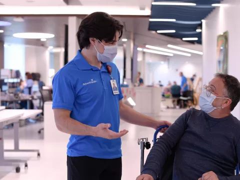A Male Volunteer Speaks with a Patient in a Hospital.