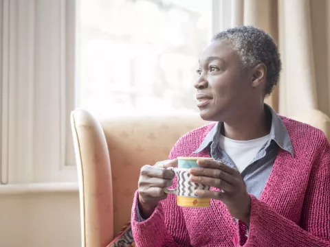 Enjoying her morning coffee, a mature woman reflects on life.