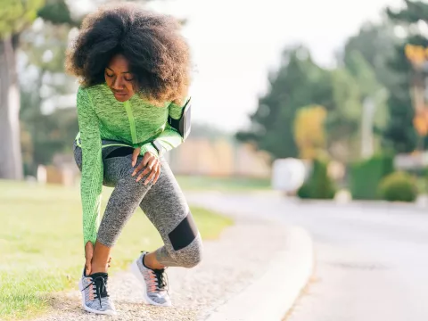 A woman checking her ankle during her run.
