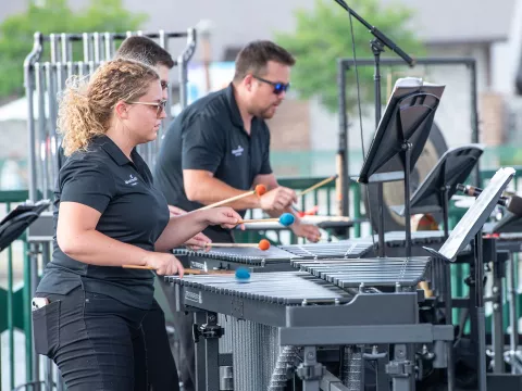 Members of the AdventHealth Orchestra playing mallet percussion instruments while outdoors.