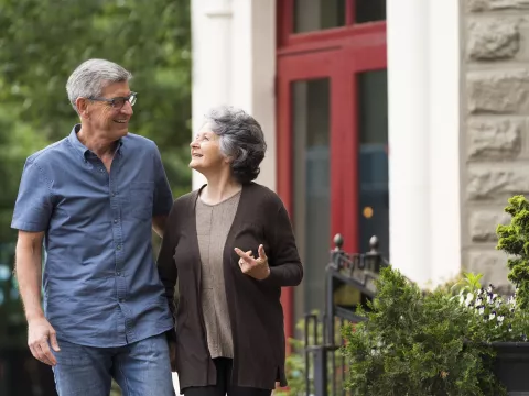 A senior man and woman walking outside of a building.