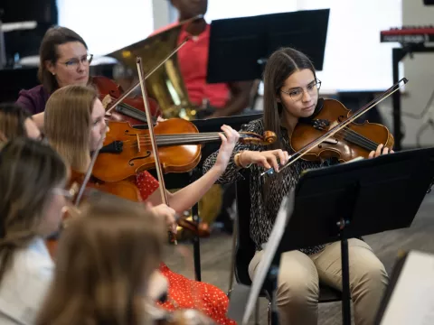 Ivanna Mirabal Molina, right, rehearses with the AdventHealth employee orchestra.