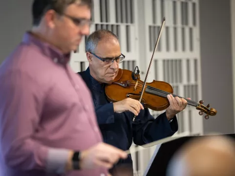 Director Richard Hickam and principal violinist Paulo Pereira practice with the AdventHealth employee orchestra.