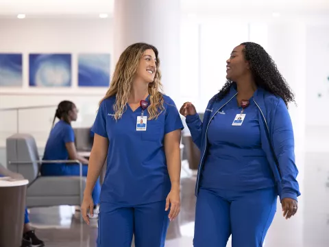 Two nurses walking together having a conversation.