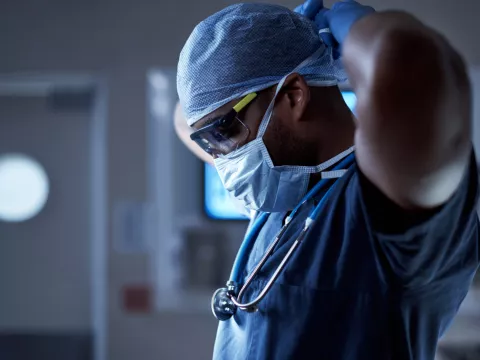 A surgeon puts on a mask.