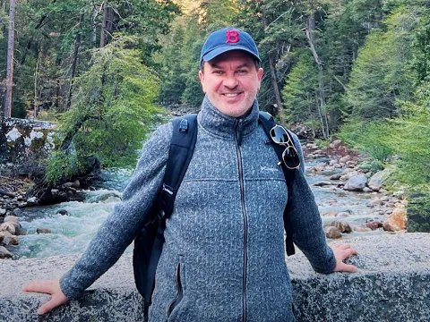 Alex Frost standing on a bridge over a river.