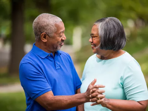 An elderly couple, enjoying each other company  while grabbing hands in the park. 