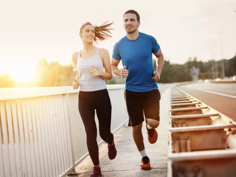 A Young Couple jogging at sunset by a road