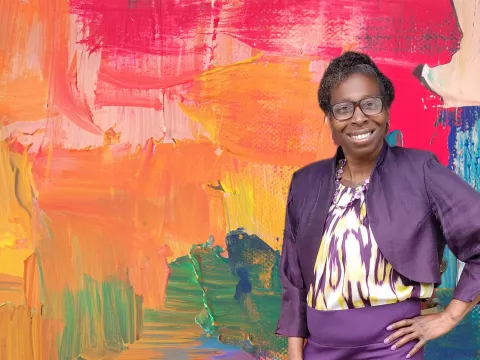 Denise Giles in front of a painterly background.
