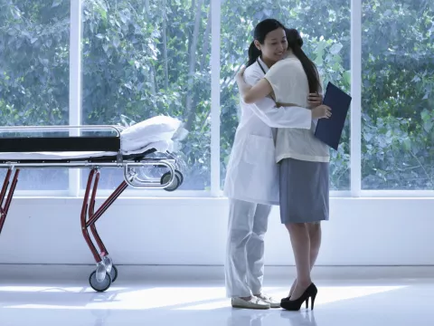 Doctor hugging a transplant patient in a large hallway, near a gurney.