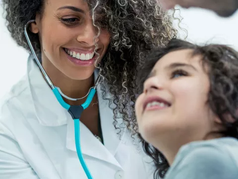 Female doctor checking a young child's heartbeat