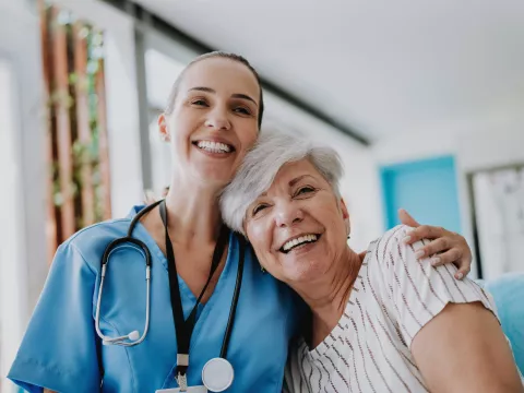 Doctor and senior woman patient hugging.