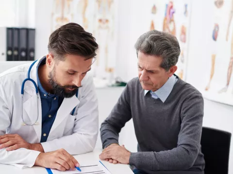 A doctor reviewing test results with a male patient at an appointment.