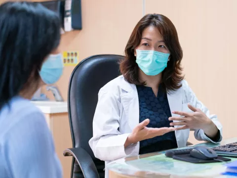 A doctor and patient during an office visit wearing masks.