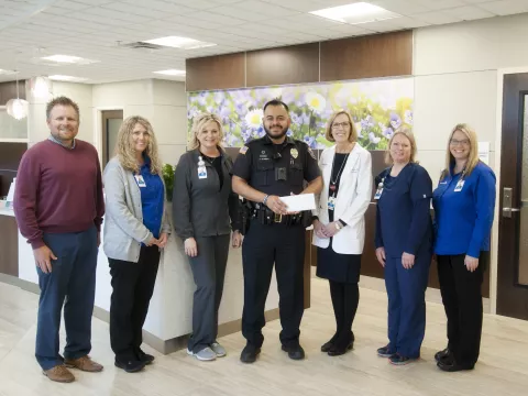 A group of people with a police officer holding an award.