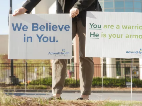 Man holding a sign saying "We believe in you".