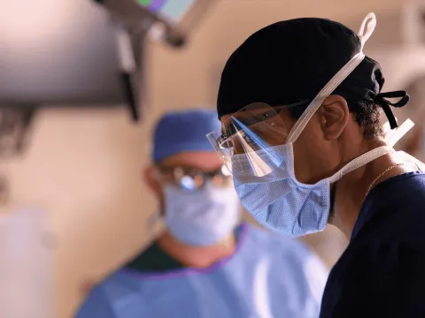 A surgeon wearing a mask and face shield.
