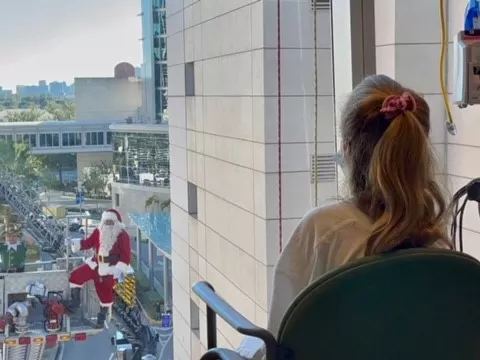 A young patient spots Santa outside her window at AdventHealth for Children. 